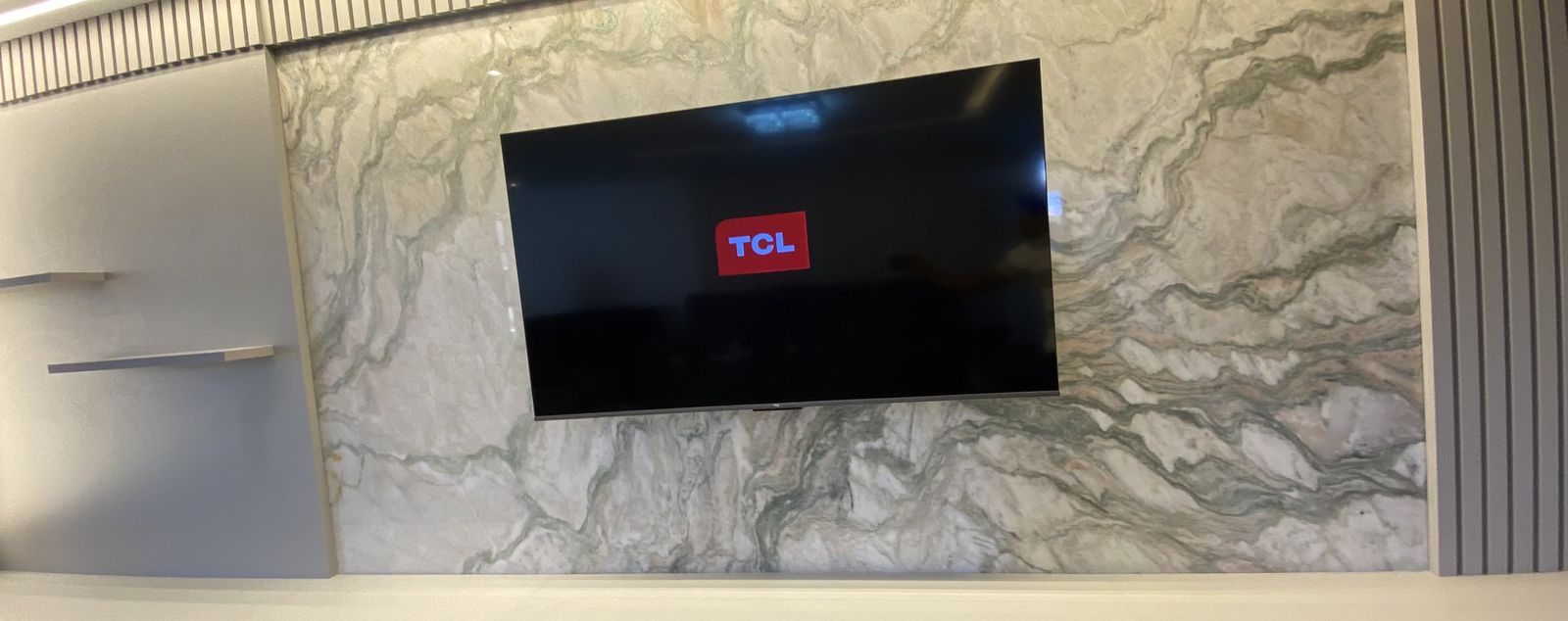 Painel de mármore atrás da TV, em sala de estar