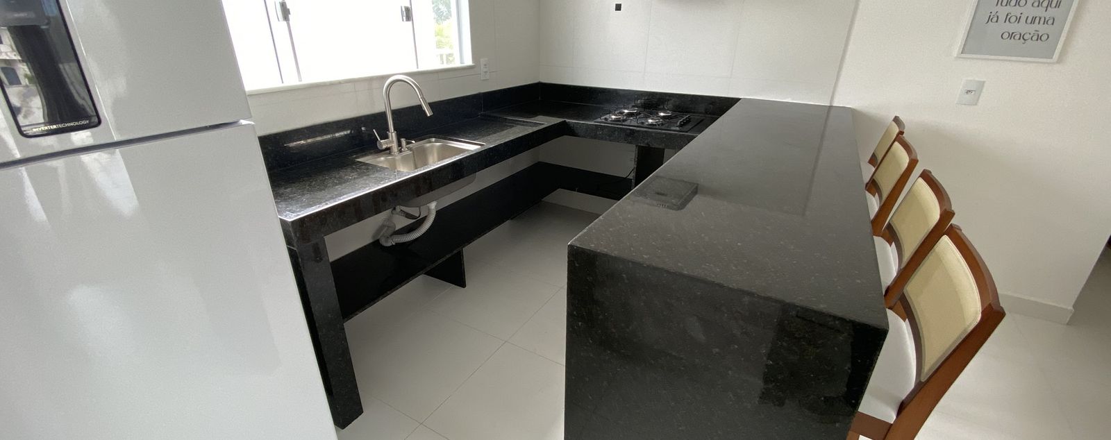 Cozinha em L com bancada de granito preto e ilha