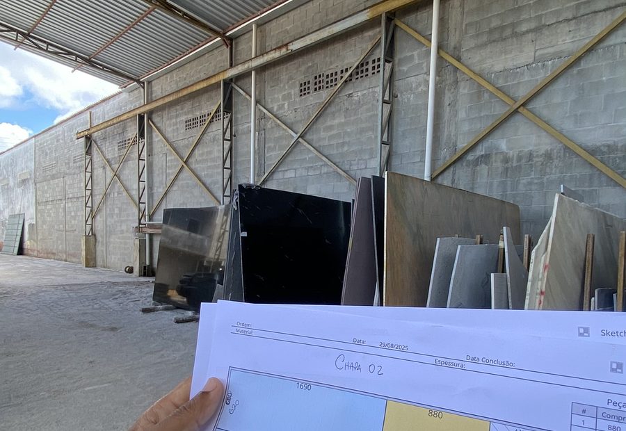 Projeto impresso em mãos dentro do galpão, com as chapas ao fundo